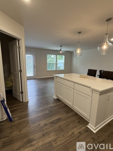 A kitchen with white cabinets and a wooden floor.