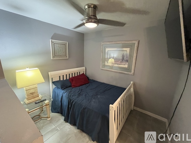 A bedroom with a bed, nightstand, lamp, and a painting on the wall.
