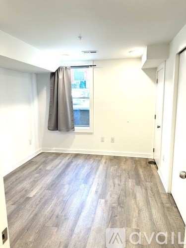 A room with wooden flooring and a window with curtains.