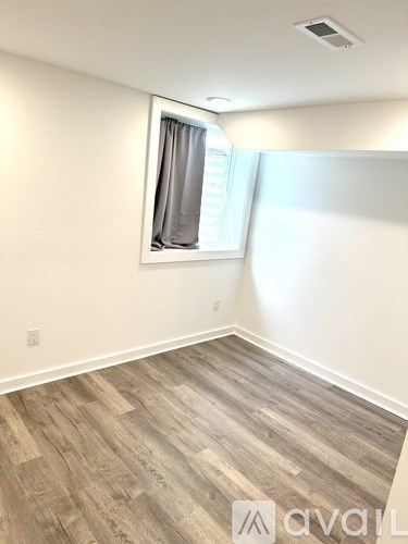 A room with wooden flooring and a window with curtains.