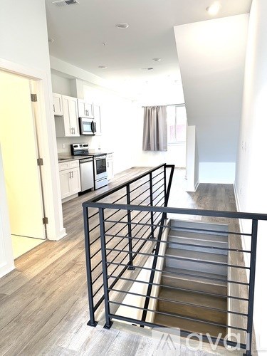 A staircase with a metal railing leads to a brightly lit room.