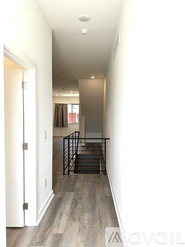A long hallway with a white door and a black railing.