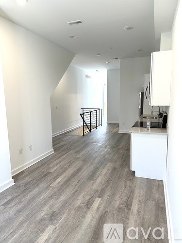 A spacious room with wooden flooring and white walls.