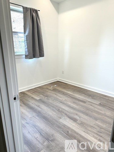 A room with a grey floor and a window with a grey curtain.