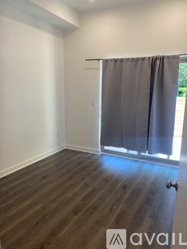 A room with wooden flooring and a sliding door with curtains.