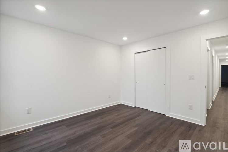 A room with wooden flooring and white walls, with a door on the right side.