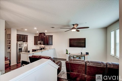 A living room with a brown leather couch and a ceiling fan.