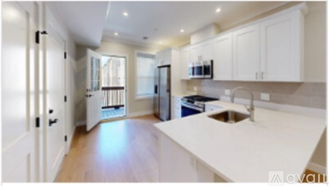 A kitchen with white cabinets and a wooden floor.