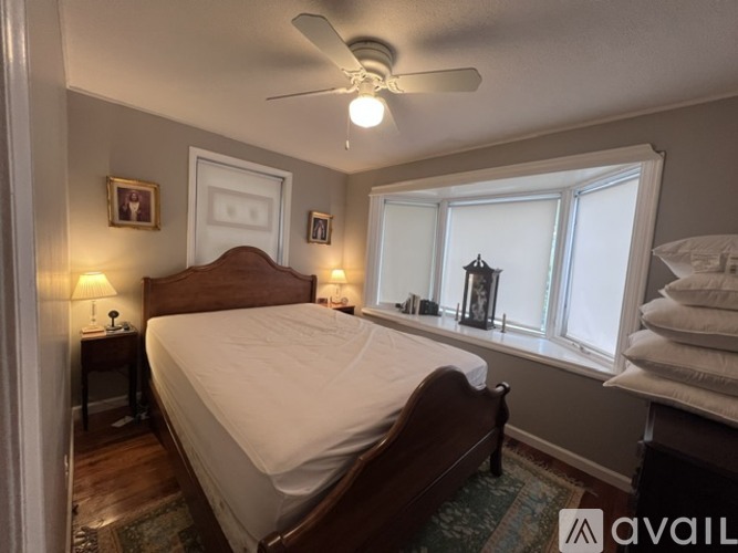 A bedroom with a bed, two lamps, and a ceiling fan.