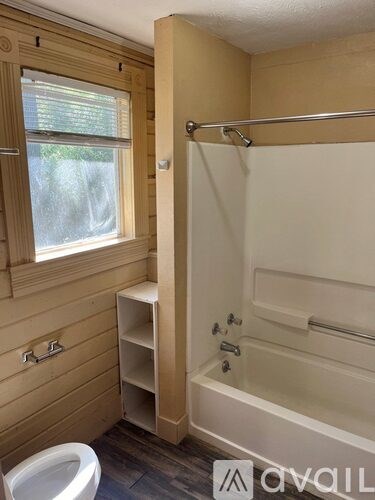 A bathroom with a tub, toilet, and window.