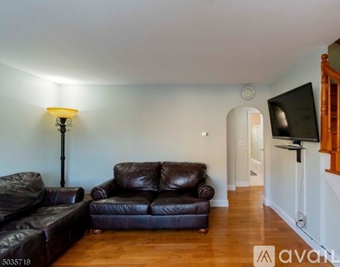 A living room with a brown leather couch and a lamp.