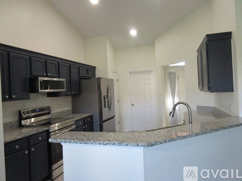 A kitchen with black cabinets and a granite countertop.