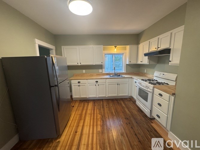 A kitchen with wooden floors and white cabinets.
