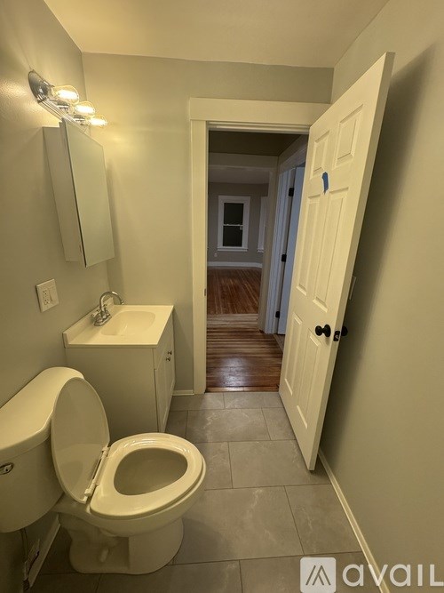 A bathroom with a toilet, sink, and mirror.