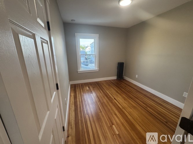 A room with wooden flooring and a window overlooking a street.
