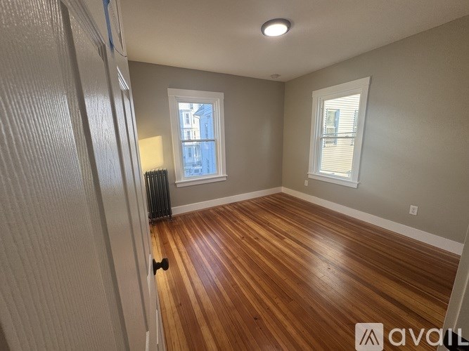 A room with wooden floors and two windows.