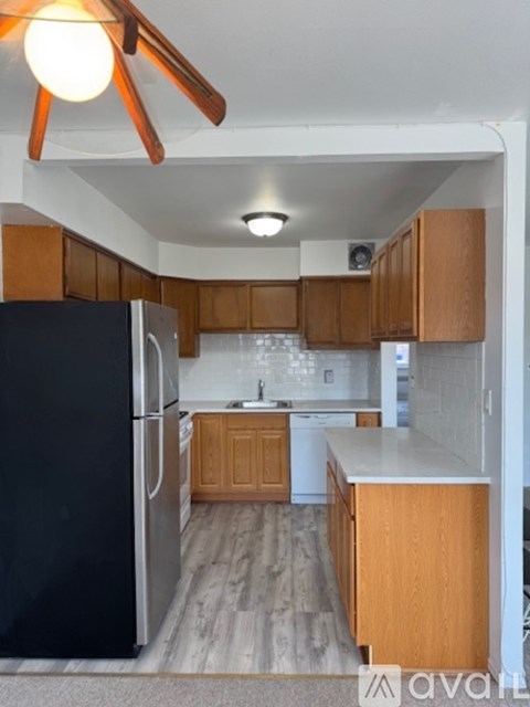 A kitchen with wooden cabinets and a black fridge.