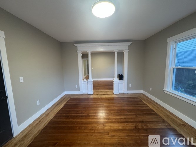 A room with wooden floors and a window on the right side.