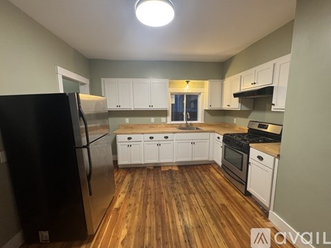 A kitchen with wooden floors and white cabinets.