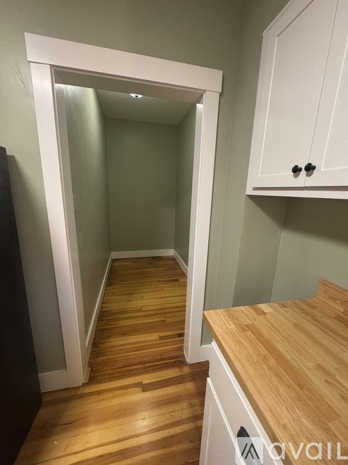 A hallway with wooden floors and white walls.
