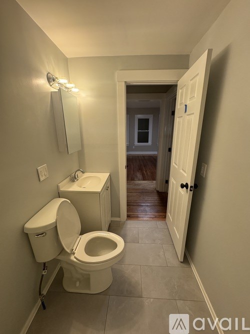 A bathroom with a toilet, sink, and mirror.