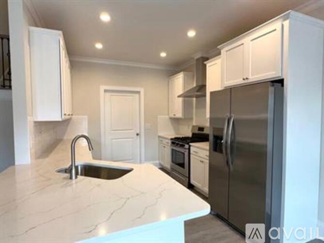 A kitchen with white cabinets and a marble countertop.