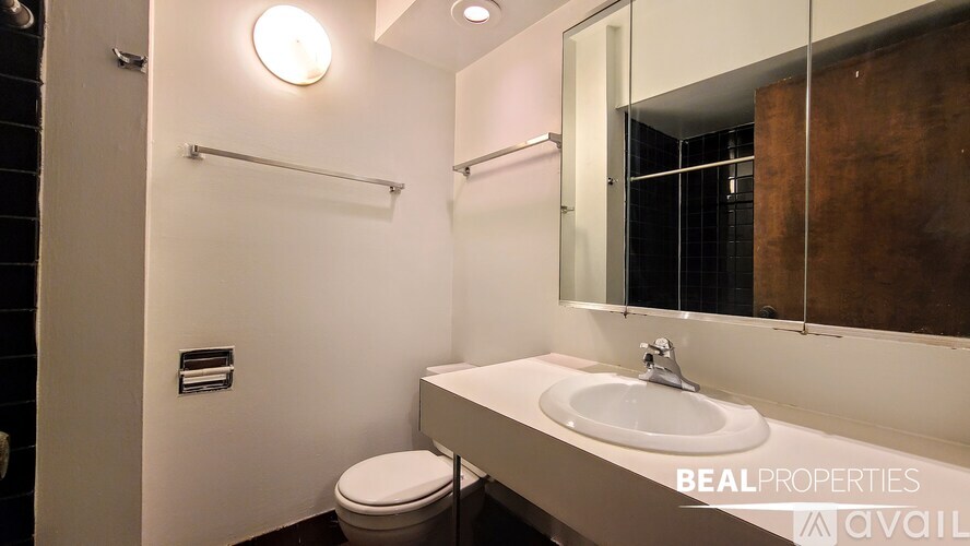 A bathroom with a toilet, sink, mirror, and towel rack.