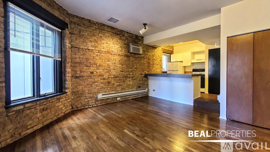 A room with a brick wall and wooden flooring is available for rent.