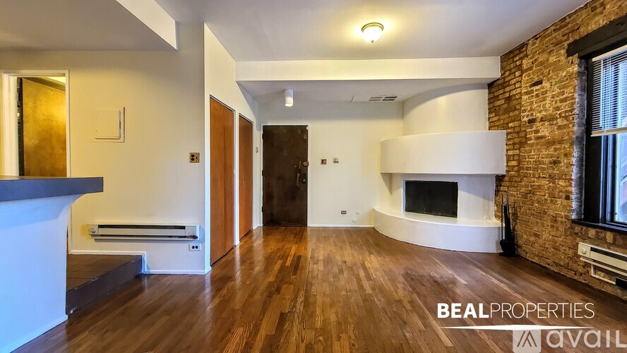 A spacious living room with a fireplace and a brick wall.