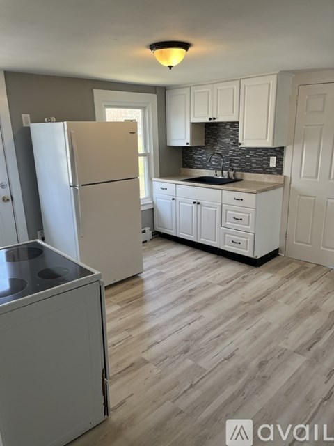 A kitchen with a white fridge and cabinets.