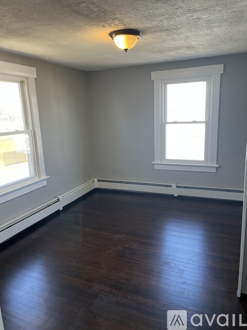 A room with a window and a wooden floor.