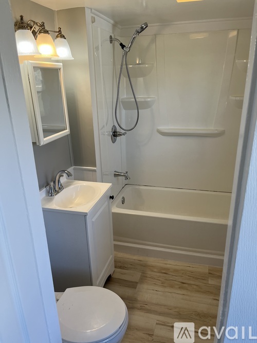 A white toilet is in a small bathroom with a walk-in shower.