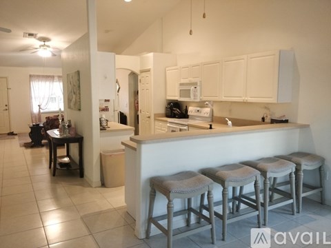 A kitchen with white cabinets and a bar stool.