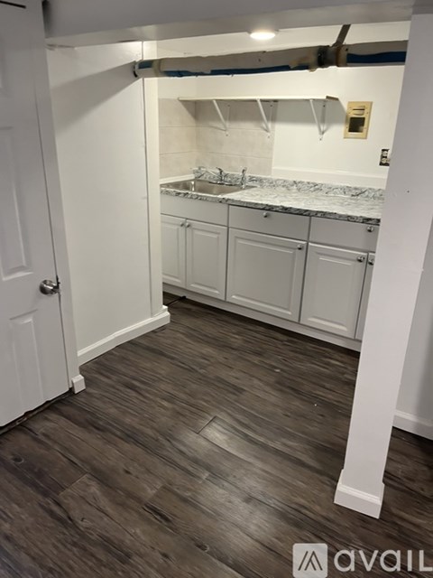 A kitchen with white cabinets and a wooden floor.