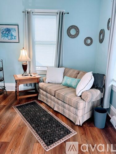 A living room with a couch, a table with a lamp, and a rug on the floor.