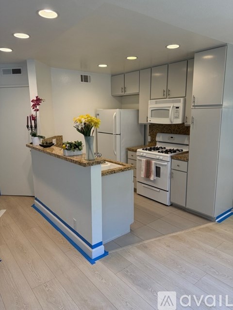 A kitchen with white appliances and a marble countertop.