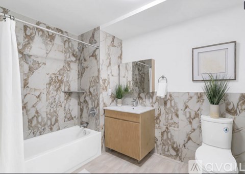 A bathroom with a marble patterned shower curtain and a wooden vanity.