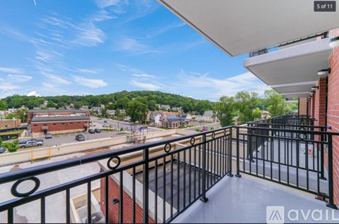 A balcony with a black railing overlooks a parking lot and buildings.