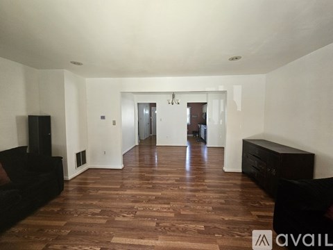 A living room with a black couch and wooden floors.