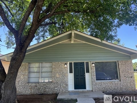 A house with a stone facade and a black door is for sale.