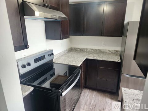 A kitchen with dark wood cabinets and a stainless steel refrigerator.