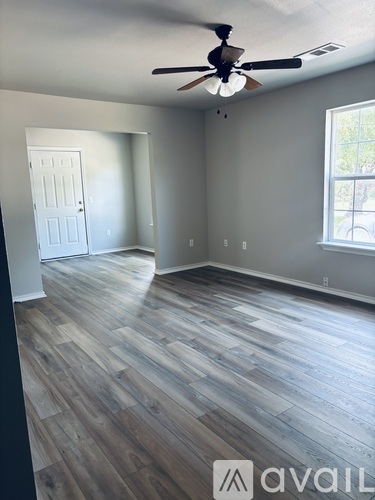 A room with a ceiling fan and wood flooring.