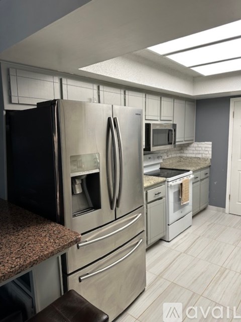 A kitchen with a black refrigerator and stainless steel appliances.