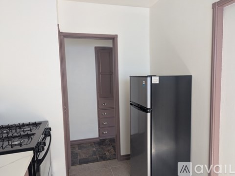 A kitchen with a stove, a refrigerator, and a door.