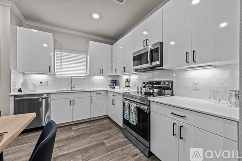A modern kitchen with white cabinets and a wooden table.