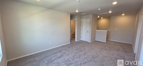 A spacious room with carpeted floor and white walls.