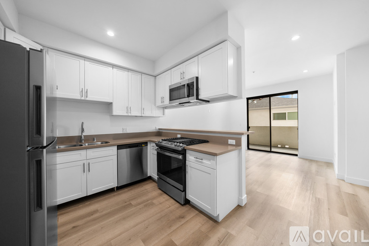 A modern kitchen with white cabinets and wooden flooring.