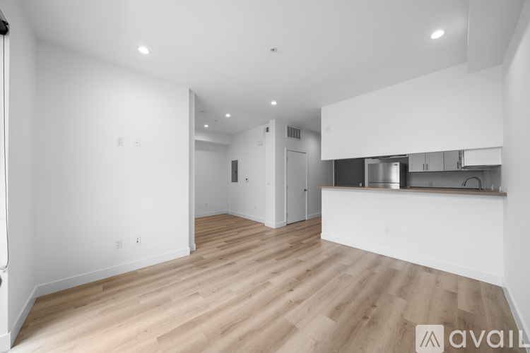 A spacious room with wooden flooring and white walls.