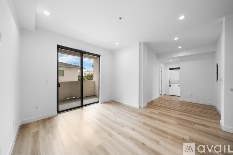 A spacious room with wooden flooring and a sliding glass door leading to a balcony.