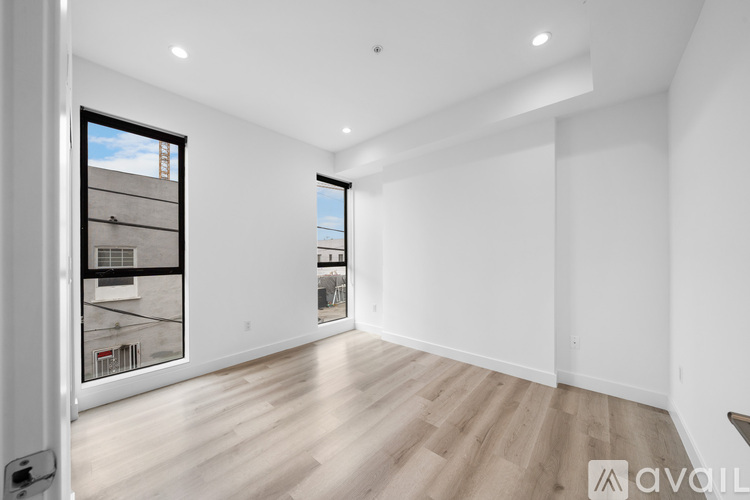 A spacious room with wooden flooring and a large window.